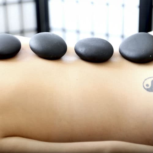 Four heated massage stones placed in a row along a client's back