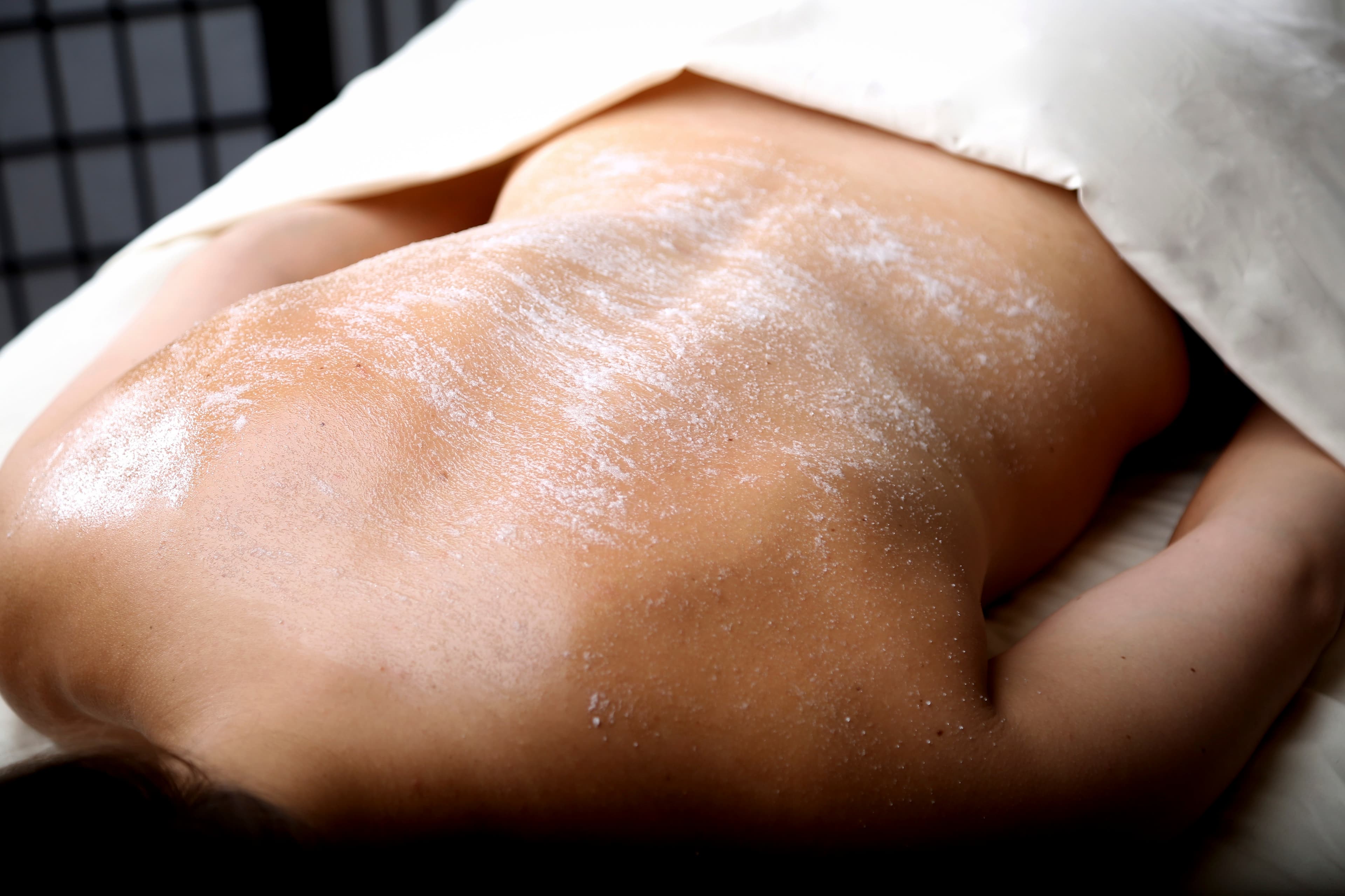 A body scrub being applied to a client's back during a spa treatment
